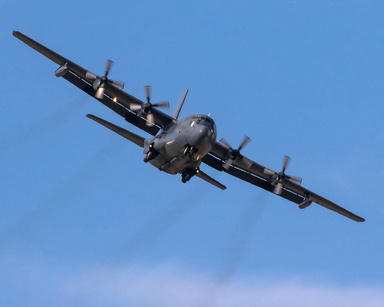 Banking overhead against a blue sky, four propellers turning