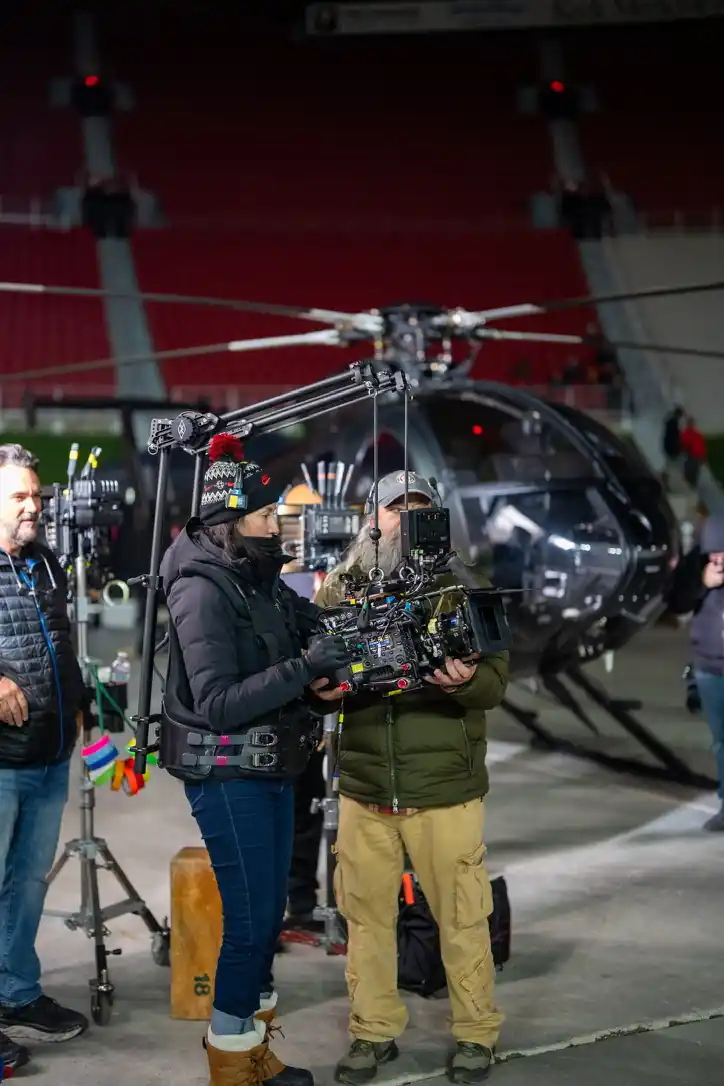 Camera crew with a camera rig in front of a black helicopter