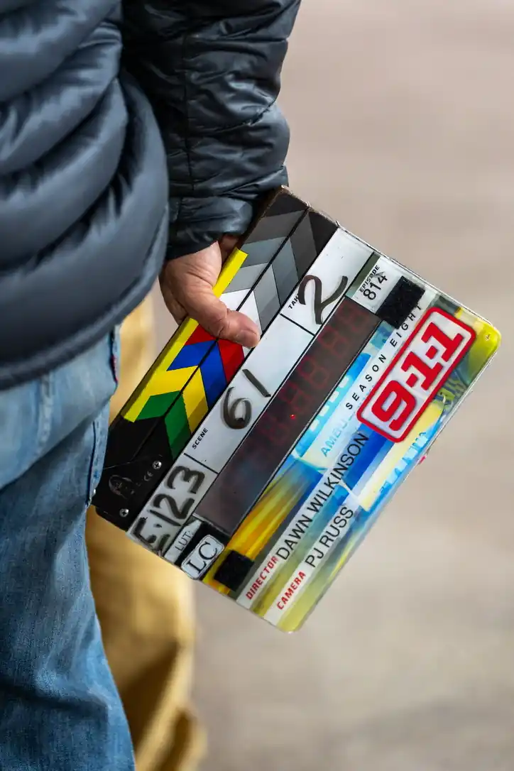 Hand holding a clapperboard on set