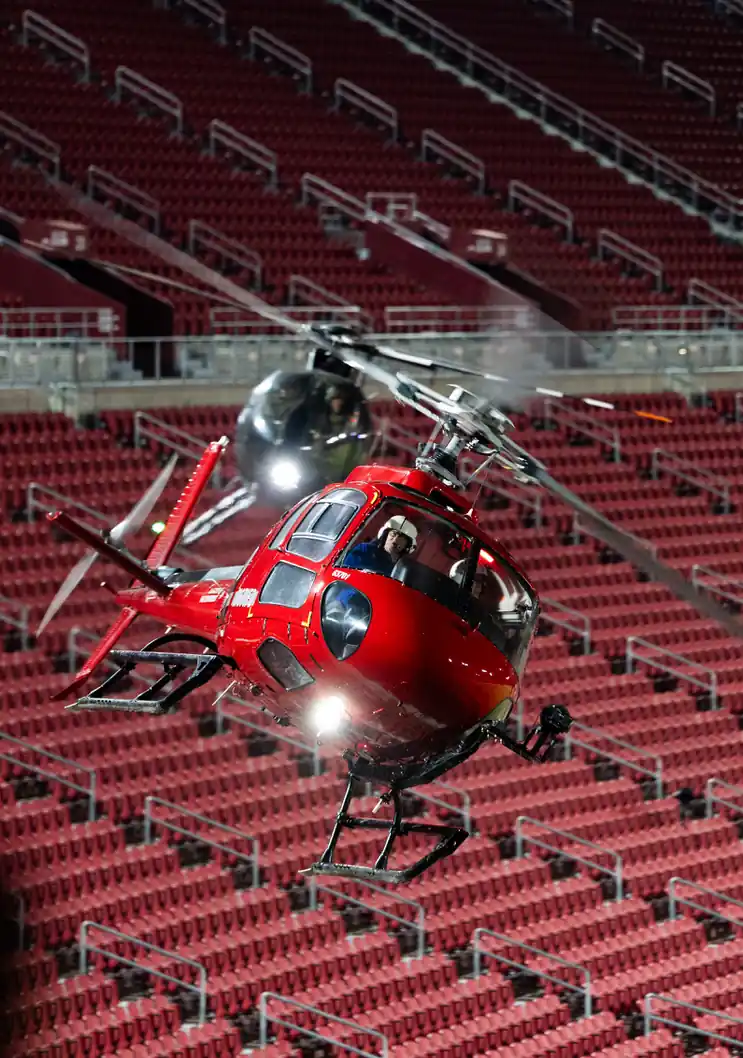 Red helicopter hovering inside a stadium