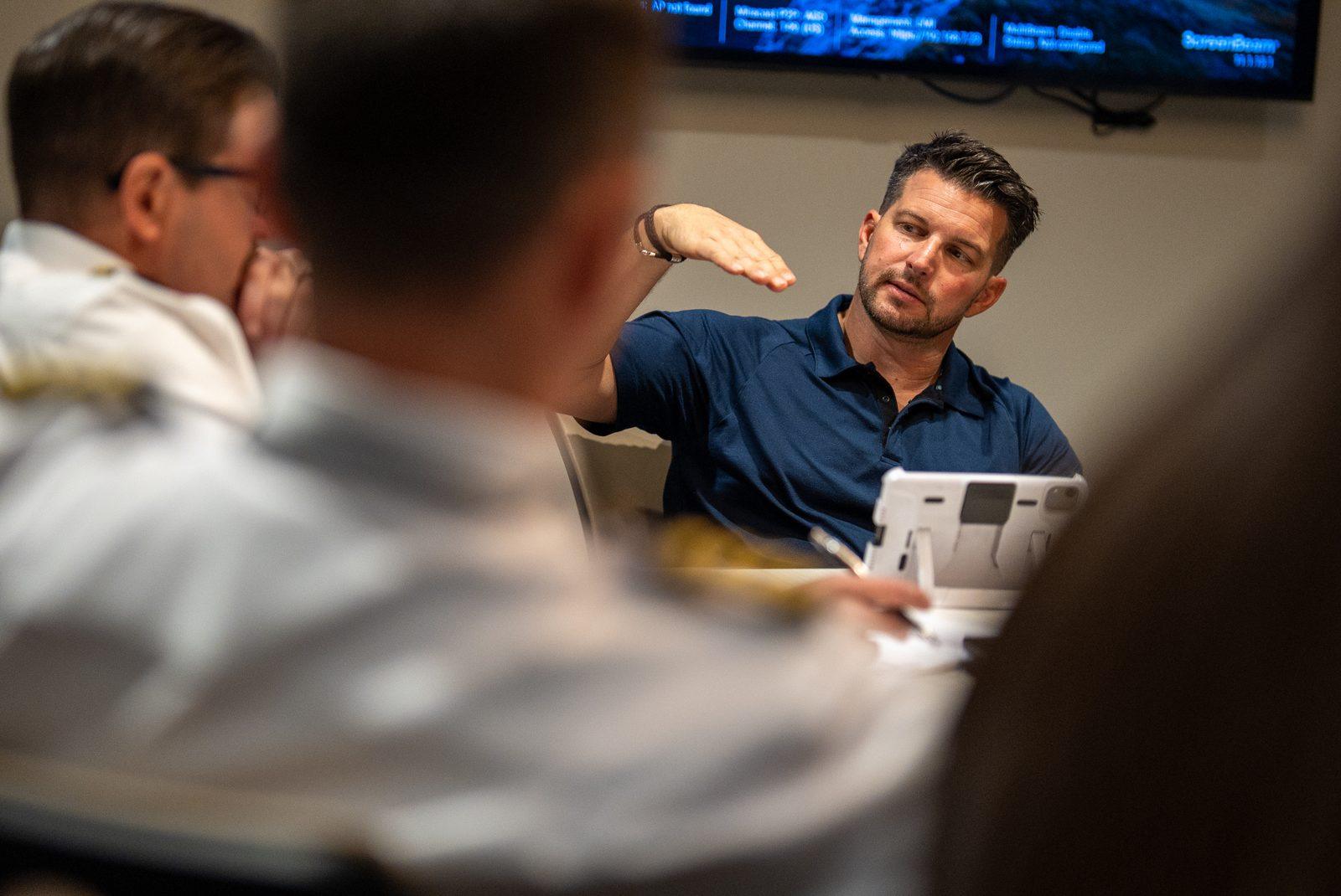 Kevin LaRosa II gesturing while explaining a plan to people seated around a table