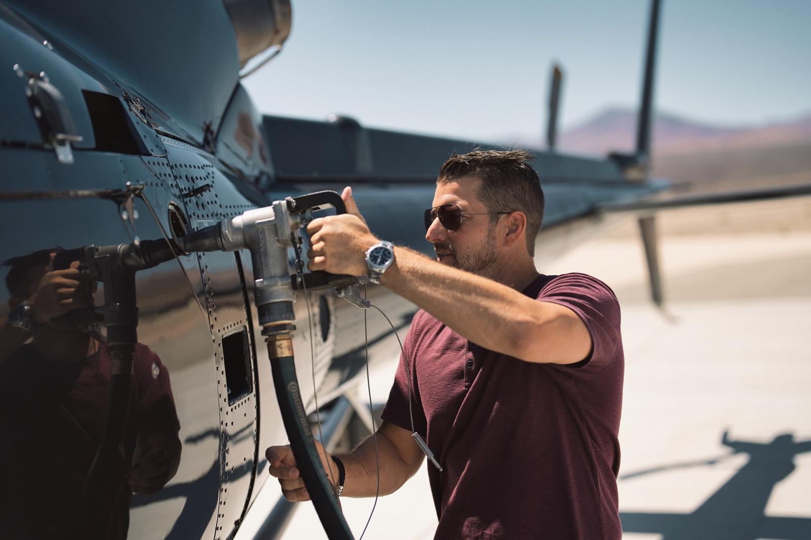 Kevin LaRosa II holding a camera beside a helicopter on the ramp