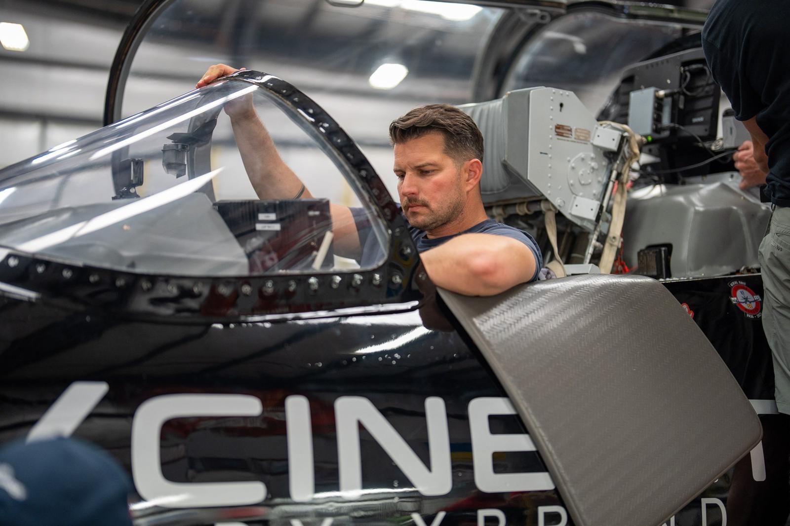Kevin LaRosa II seated in the open cockpit of the Cinejet in a hangar