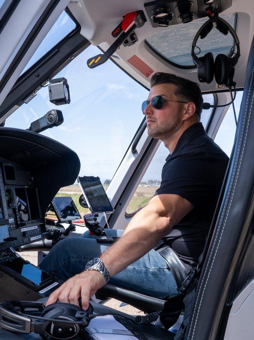 Kevin LaRosa II in sunglasses, seated at the controls in a helicopter cockpit