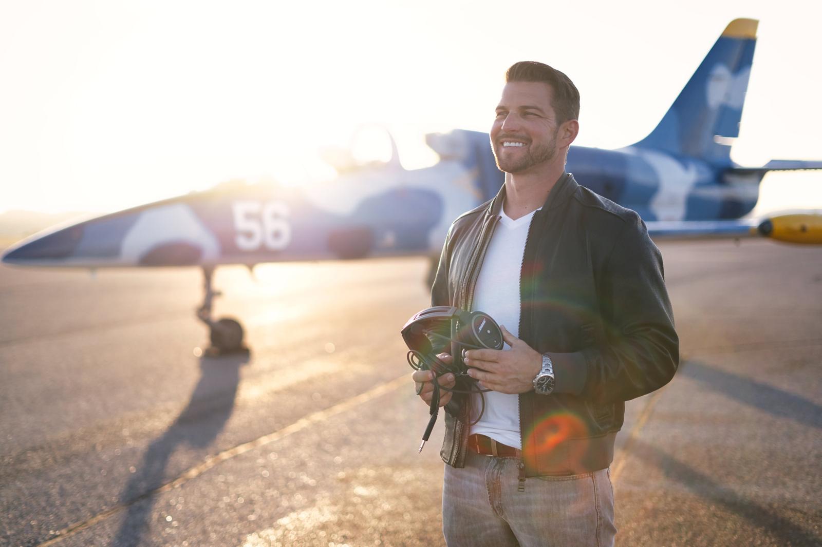 Kevin LaRosa II holding a headset in front of the blue-camo L-39 #56 at sunset