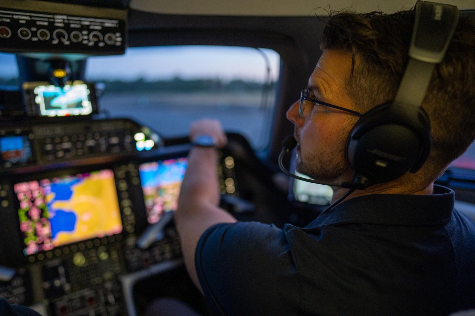 Kevin LaRosa II in a jet cockpit at dusk, wearing a headset
