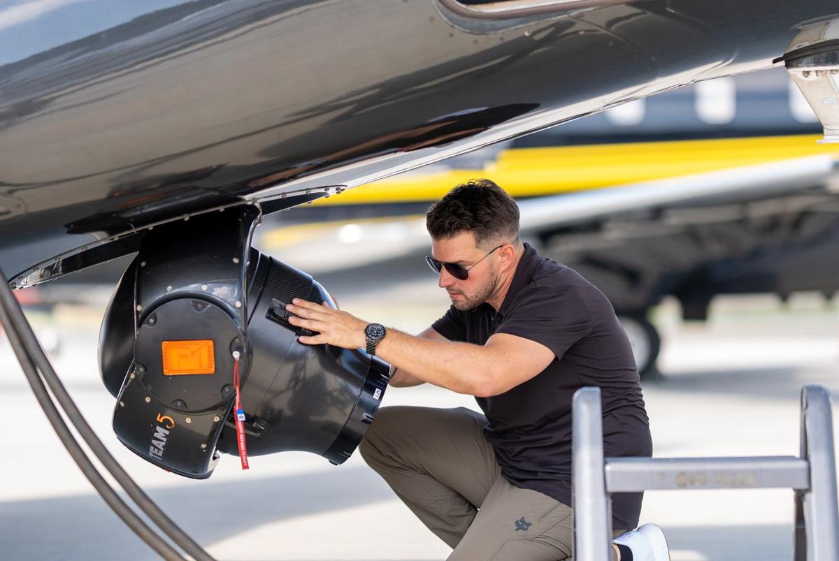 Kevin LaRosa II checking a camera mount under a helicopter