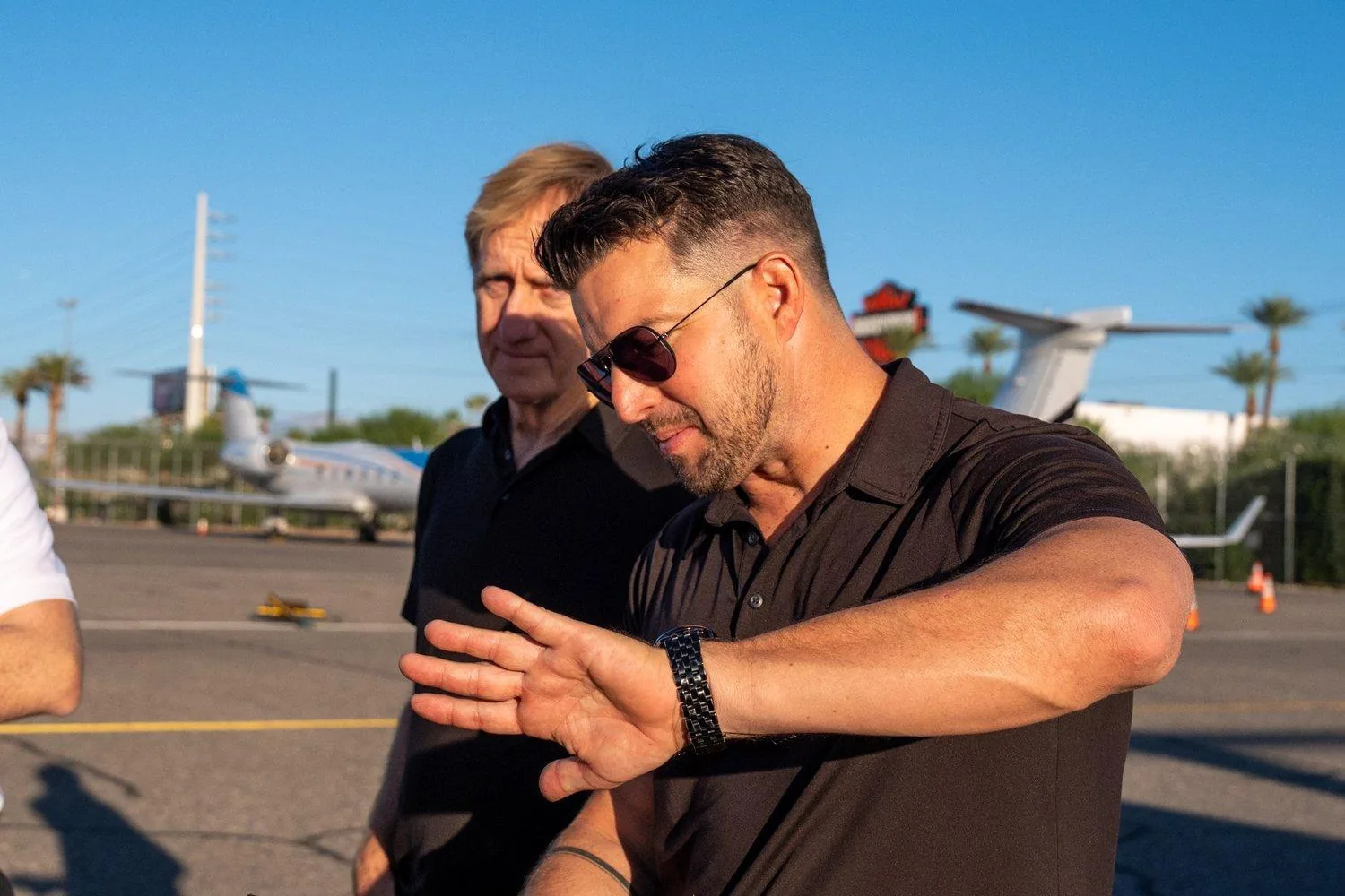 Kevin LaRosa II on the ramp, walking through a maneuver with his hand, jets parked behind